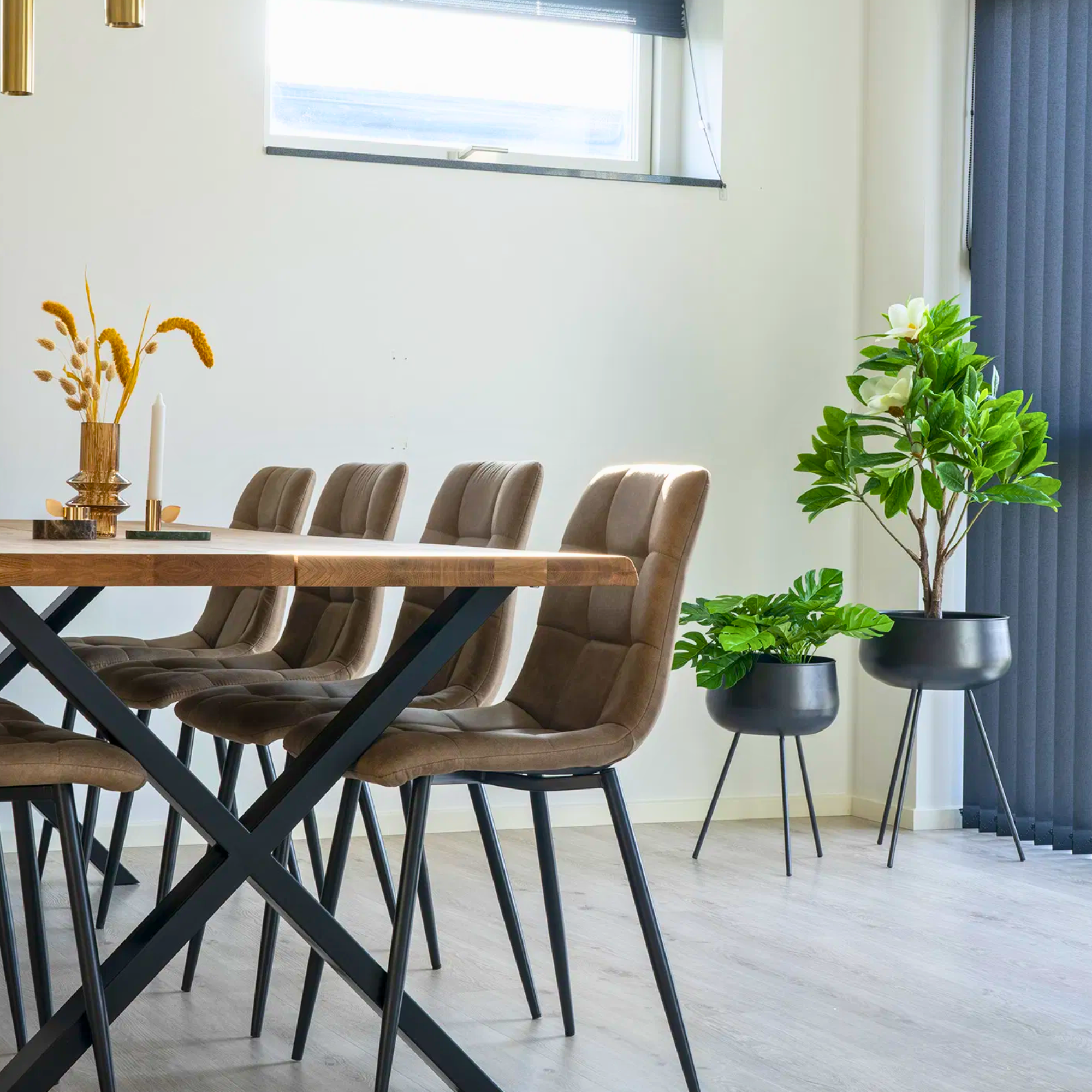 House Nordic Middelfart eetkamerstoelen in lichtbruin microvezel met zwarte poten rond houten eettafel in modern Scandinavisch interieur met planten.