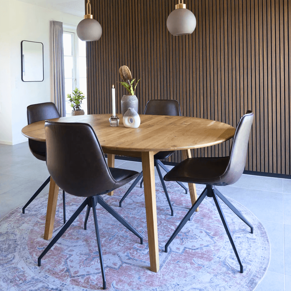 Interieurfoto van de Monaco eetkamerstoelen van House Nordic in donkerbruin PU-leer met zwarte metalen poten, rond eettafel in moderne eetkamer.