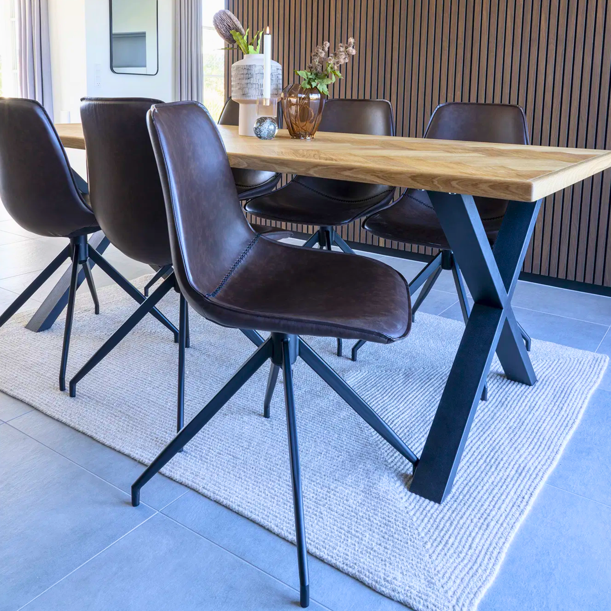 Donkerbruine Monaco eetkamerstoelen van House Nordic in PU-leer met zwarte metalen poten, geplaatst rond een houten eettafel in modern interieur.