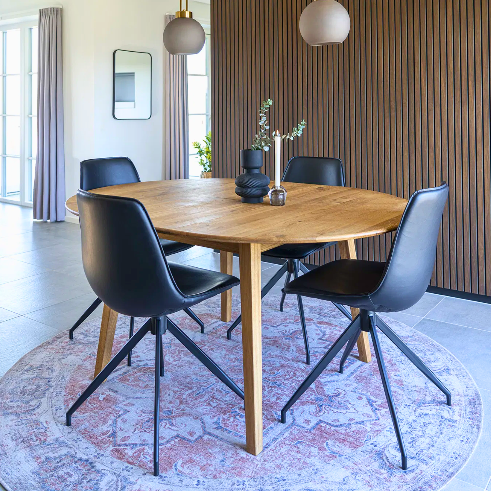 Interieurfoto van de Monaco eetkamerstoelen van House Nordic in zwart PU-leer met zwarte metalen poten, rond eettafel in moderne eetkamer.