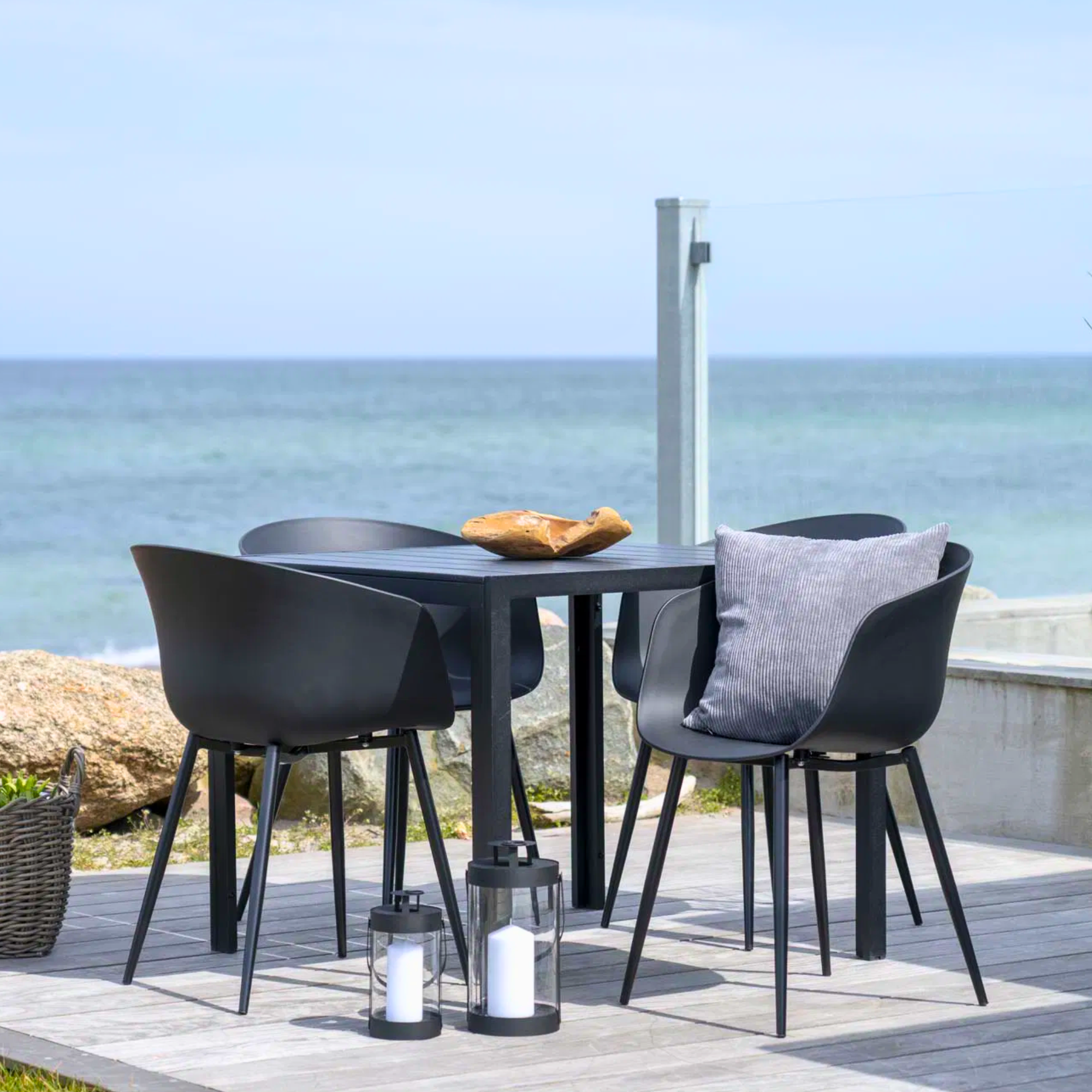 Zwarte House Nordic Roda eetkamerstoelen op terras met uitzicht op zee – modern Scandinavisch design voor binnen en buiten.
