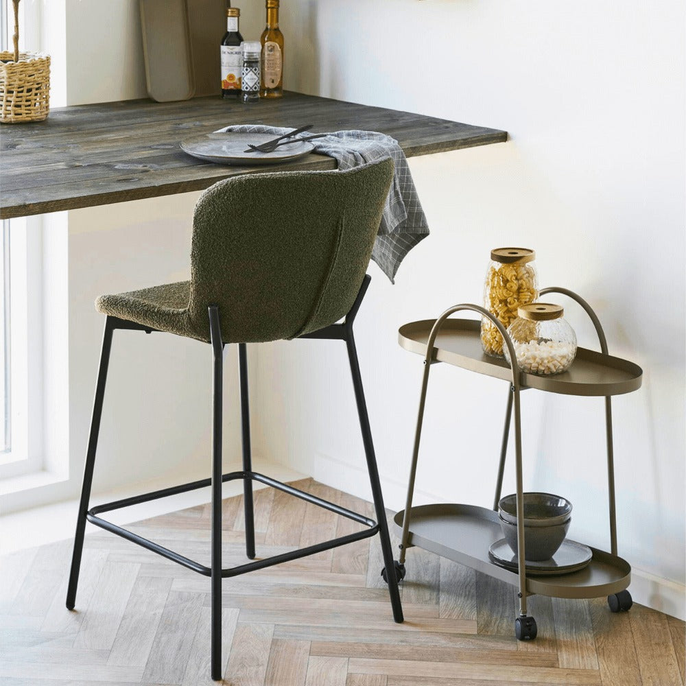 Maceda barkruk in donkergroen bouclé met zwarte poten, geplaatst aan een houten bar in een modern Scandinavisch interieur van House Nordic.