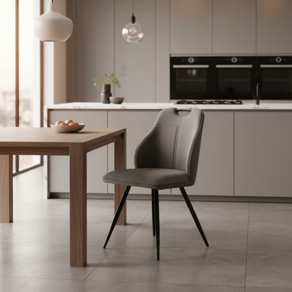 RV Design Adele eetkamerstoel in antraciet Retro Bliss stof geplaatst aan houten tafel in een moderne keuken met lichtgrijze kasten en designverlichting.