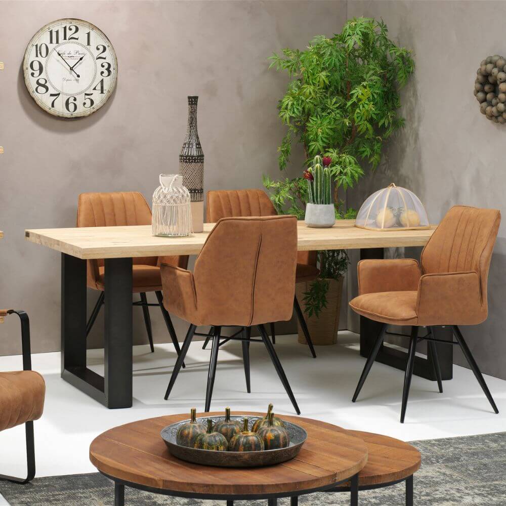 RV Design Clark armstoelen in warme cognac tint rond een houten eettafel in een sfeervol interieur.