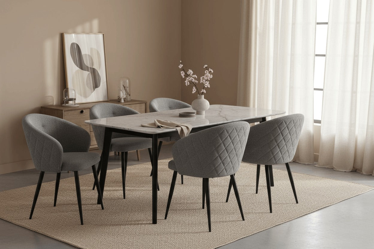 RV Design Kelly stoelen in staalgrijze teddy stof rond een moderne eettafel met zwart metalen onderstel in een warm interieur.