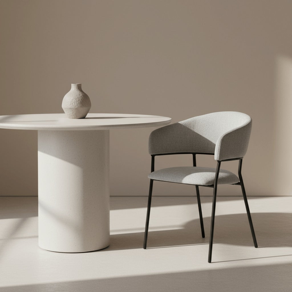 RV Design Liam armstoel in lichtgrijs naast een ronde minimalistische tafel in een zachte, moderne interieursetting.