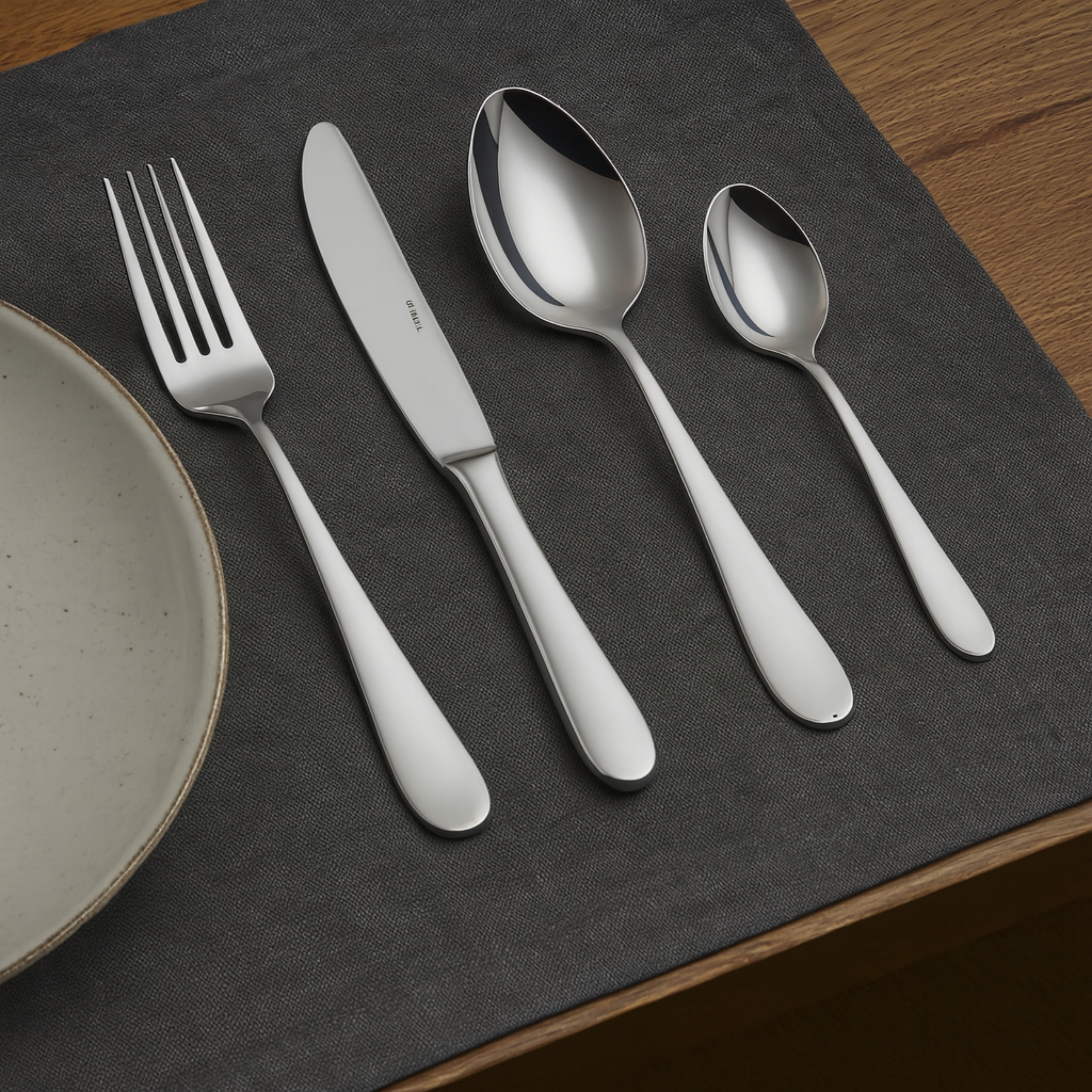 Sambonet Astrid 24-delige bestekset – roestvrijstalen vork, mes, lepel en koffielepel op gedekte tafel met grijs tafellaken